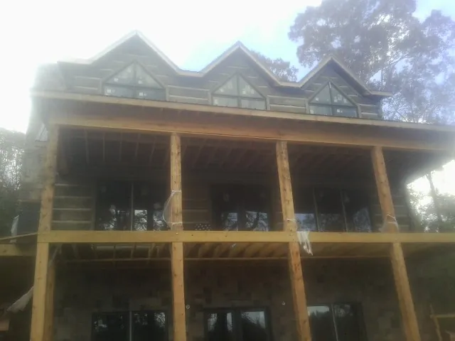 Dormers and porch framing on a large log home under construction — Roof Coating work by our crew in Leslie
